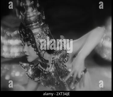 Scene from the Film 'Piccadilly': The Actor Anna May Wong Performing a Chinese Dance in Costume, 1920s. Anna May Wong as Shosho. Wong Liu Tsong (1905-1961), known professionally as Anna May Wong, was considered the first Chinese American film star in Hollywood, as well as the first Chinese American actress to gain international recognition. Her varied career spanned silent film, sound film, television, stage, and radio. From &quot;Time To Remember - Came The Dawn&quot;, 1925 (Reel 4); peek at the British Film Industry of the 1920s - clips from great silent films and newsreels. Stock Photo