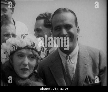 Mary Pickford and Douglas Fairbanks Senior Smiling for the Camera, 1920. There was '...excitement, when into a British port, sailed a couple that all the world seemed crazy to meet. Idols of the Silver Screen have always provided a great attraction, but no subsequent display of fan worship has ever quite come up to what those two received. A golden-haired little Hollywood actress and her romantic, acrobatic husband.. Mary Pickford and Douglas Fairbanks'. From &quot;Time To Remember - The Plunge Into Peace&quot;, 1920 (Reel 3); events of 1920 - weddings, women's rights, industrial unrest and pr Stock Photo