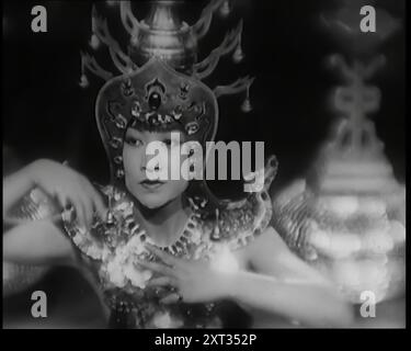 Scene from the Film 'Piccadilly': The Actor Anna May Wong Performing a Chinese Dance in Costume, 1920s. Anna May Wong as Shosho. Wong Liu Tsong (1905-1961), known professionally as Anna May Wong, was considered the first Chinese American film star in Hollywood, as well as the first Chinese American actress to gain international recognition. Her varied career spanned silent film, sound film, television, stage, and radio. From &quot;Time To Remember - Came The Dawn&quot;, 1925 (Reel 4); peek at the British Film Industry of the 1920s - clips from great silent films and newsreels. Stock Photo