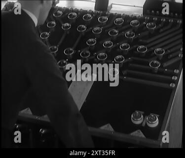 A Male Civilian Using System of Levers and Cogs To Make the Automated Railway Marshalling System Work and Empty Wagons Move on Their Own, 1931. 'Something else for the schoolboy in all of us, something wonderfully complex and awe-inspiring. That new, automatic marshalling yard. One man, whom progress has endowed with enormous power, so much did he control. The goods traffic of a nation being pushed and shunted about by the touch of a finger. What couldn't we do?' From &quot;Time To Remember -  A New Era&quot;, 1931 (Reel 3); documentary about the world in the early 1930s. Stock Photo