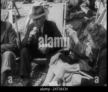 A Group of Two Men and Two Women Sitting on Deckchairs on the Beach at  Brighton and Eating Ice Creams, 1939. From &quot;Time To Remember -  The Reluctant Warriors&quot;, 1939 (Reel 1); documentary about events of 1939 - preparations for war and then hostilities break out. Stock Photo