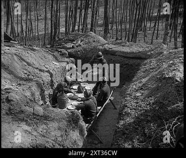 French Soldiers Eating a Meal in a Dug Out, 1940. Second World War. 'So when's dinner? All that digging makes a man hungry'. From &quot;Time To Remember -  Run Rabbit Run&quot;, 1940 ( Reel 1); documentary film about events of early months of 1940. Stock Photo