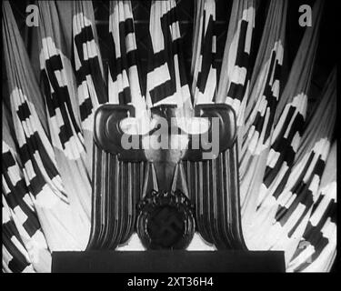 German Eagle Statue With German Flags Behind Bearing the Nazi Swastika, 1937. From &quot;Time To Remember -  Sense Of Values&quot;, 1937 (Reel 4); documentary film about the events of 1937, war in the Far East, build up to war in Europe. Stock Photo