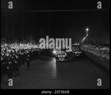 Nazi Party Staff Cars Driving Down a Wide Road in Berlin with cheering crowds and Soldiers Lining Both Sides, 1937. 'The leader [Adolf Hitler] returns from his visit to Italy...the people are told that the leader is not just a man, but a flawless god, and must be treated as such - and treated as such he is. Not the return of a conquering hero, for as yet the hero has not set about his real conquests. No, this is just the return of Germany's favourite son. Something new. Something and somebody of a driving force and influence. This, unless it were destroyed, the future power and the glory of a Stock Photo