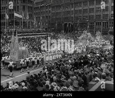 Participants Walking Alongside Floats in a Large Parade During the World Congress for Leisure Time and Recreation in Hamburg in 1936 With Hundreds of Spectators Watching, 1938. From &quot;Time To Remember -  Wind up Week&quot;, 1938 (Reel 1); documentary film about 1938 - people become aware of the growing threat of war. Stock Photo