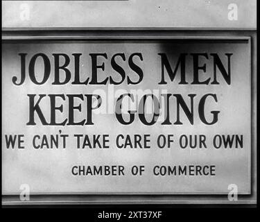 Sign reads: 'Jobless Men Keep Going - We Can Take Care of Our Own - Chamber of Commerce', 1932. The United States during the Great Depression. '...always they had to move on. A job, security, a full stomach. &quot;You want them bud? Well take this hand-out and get along with you. Move along, bud, through the Depression, better times are just around the corner&quot;.' From &quot;Time To Remember - Around the Corner&quot;, 1932 (Reel 1); diary of events in 1932 in the United States of America - Franklin Roosevelt becomes the President. Stock Photo