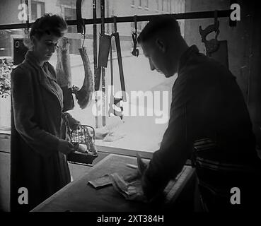 A Woman Buying Meat at a Butcher's Shop, 1942. Britain during the Second World War. '...you went on fighting the enemy in the only way you knew how, by somehow getting along, day by day, with what there was, and making it go as far as it could...[Butcher:] &quot;Really Mrs Jones, that's all the meat today&quot;. [Customer:] &quot;What, these few pieces?&quot;...[Butcher:] &quot;Your ration book, please. Turned out nice again didn't it?&quot;' From &quot;Time To Remember - The End Of The Beginning&quot;, 1942 (Reel 4); documentary film about events of 1942 and America's entry into the war. Stock Photo