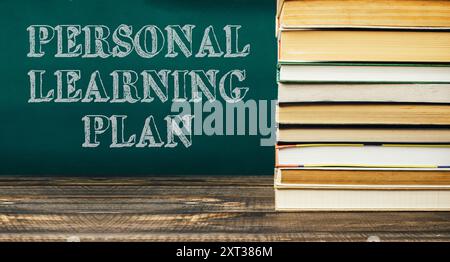 A stack of books with the words Personal Learning Plan written on a green chalkboard. The books are piled on top of the chalkboard, creating a sense o Stock Photo