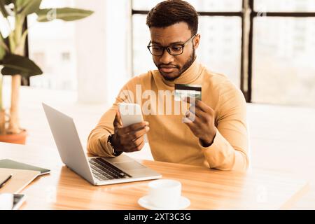 Black manager making purchases using computer and phone Stock Photo