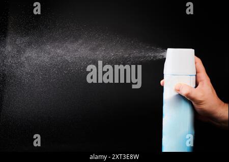 Hand hold metal spray bottle with air stream isolated on black studio background Stock Photo