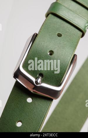 Part of a green leather classic belt with a buckle on a gray background. Stock Photo