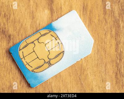 close up of a telecommunications smart phone sim card isolated on a wooden background Stock Photo