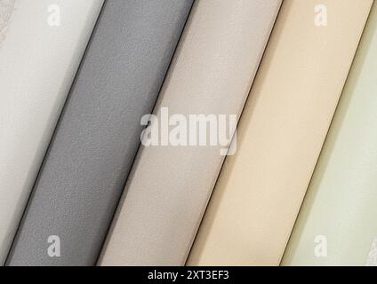 Multi-colored tubes of paper wallpaper for repairs rolled into rolls. Stock Photo