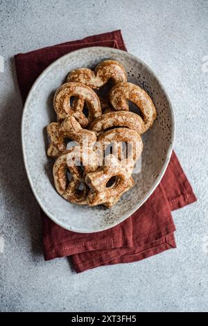 Top view of homemade gingerbread cookies in a star shape dusted with sugar spice, presented artistically in a speckled ceramic bowl on a textured gray Stock Photo