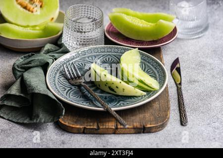 From above various organic mini melon slices artistically presented on an ornate blue patterned plate, coupled with a textured grey napkin and elegant Stock Photo
