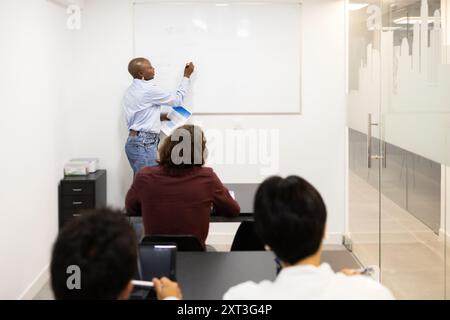 An English teacher instructs a multiethnic class of adult students, focusing on an interactive whiteboard lesson in a modern classroom The students, d Stock Photo