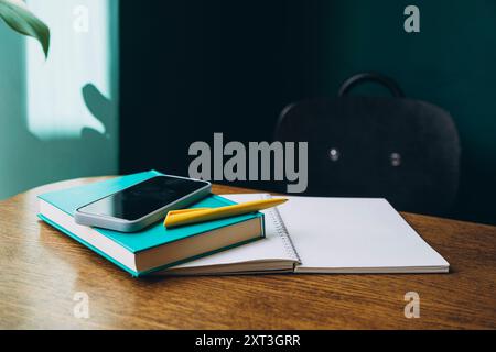 A neatly arranged desk with a smartphone, books, and stationery, prepared for a successful back-to-school season, alongside a stylish backpack. Stock Photo