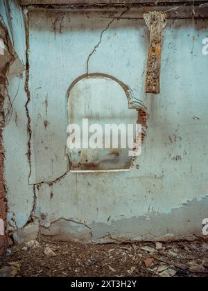 Decaying interior wall with peeling paint and visible cracks in an abandoned building. Stock Photo