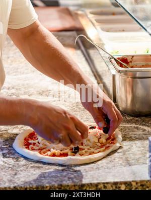 A chef adding cheese to pizza base Stock Photo - Alamy