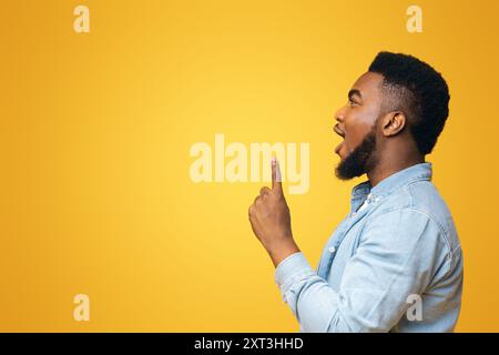 African guy looking and pointing upwards at copy space Stock Photo