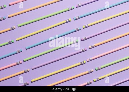 A creative flat lay of multicolored pencils ordered in parallel lines on a lavender surface, symbolizing back-to-school preparation Stock Photo