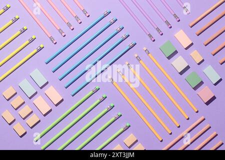 Top view of neatly organized back to school materials on a purple background, including pink, blue, yellow, and green pencils, and assorted sticky not Stock Photo