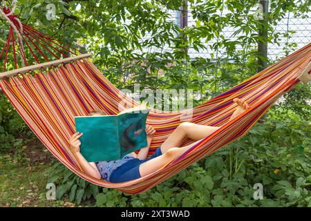 Boy lying in hammock reading a book outdoors Stock Photo - Alamy