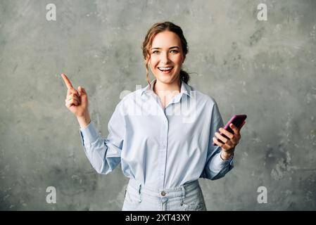 Cheerful young woman with a smartphone, enthusiastically showcasing a mobile app. Perfect for business, tech, or app promotion imagery. Isolated on a Stock Photo
