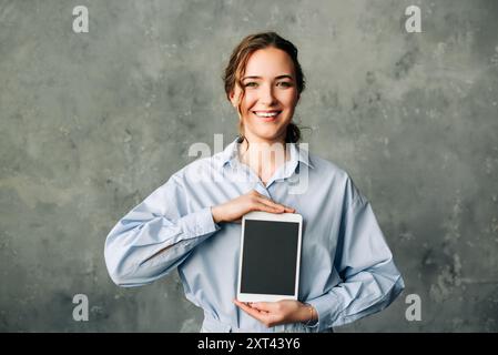 Young businesswoman smiling and holding a tablet with a blank screen. Perfect for showcasing technology, digital advertising, or app promotion. Ideal Stock Photo