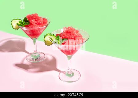 Watermelon slushie or granita cocktail drink with mint in two glasses on pink and green trendy background.  Refreshing cold summer shaved ice drink or Stock Photo
