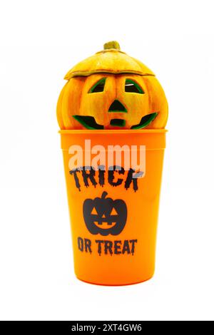 Ceramic candle holder in the shape of a halloween pumpkin sitting on an orange trick or treat plastic cup Stock Photo