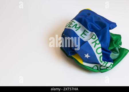 Poorly folded Brazilian flag on a white background with part of the phrase Ordem e Progresso appearing. Stock Photo