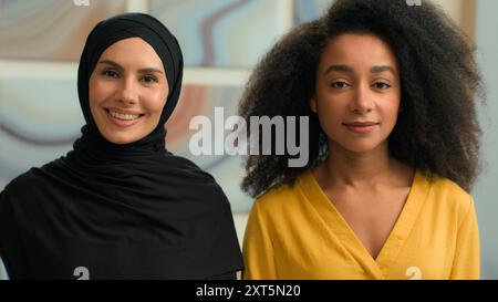 Two diverse business women girls multiracial female businesswomen African American colleagues Arabian muslim islamic in hijab coworkers friends ladies Stock Photo