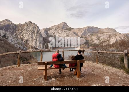 Hiking family sitting on a bench admiring the mountains Stock Photo
