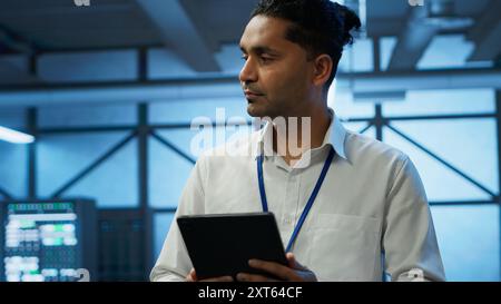Security analyst in data center monitoring security threats, implementing cybersecurity measures. Expert ensuring compliance with regulations to protect data center assets, camera A Stock Photo