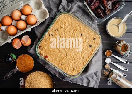 Uncooked Middle Eastern Breakfast Bake: Breakfast casserole made with bulgur, dates, eggs, milk, and spices in a glass baking dish on wooden table Stock Photo