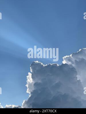 sunrays piercing through the clouds on a sunny summer day. Stock Photo