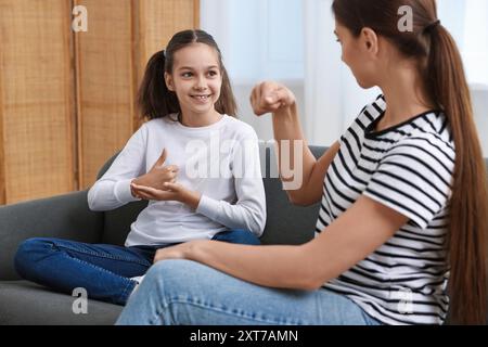 Woman and her daughter using sign language for communication at home Stock Photo