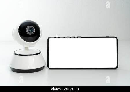 Smart home security camera. Webcam white background. Copy space. Smartphone video surveillance concept. Mobile phone with security camera. Copy space. Stock Photo