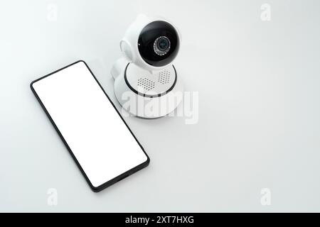 Smartphone mockup with wifi sign near white surveillance camera on white background. A smart home security camera with a blank lens isolated on white Stock Photo