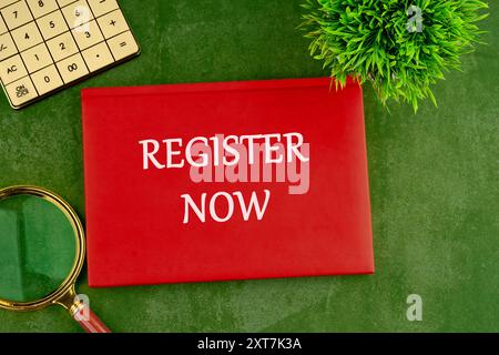 REGISTER NOW words written on the cover of a business book on a green saturated background Stock Photo