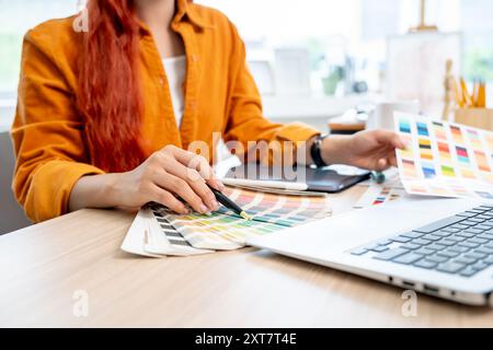 A close-up image of a female graphic designer working at her desk in the studio, selecting colors from a set of swatches. creativity job concept Stock Photo