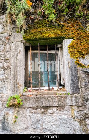 Old window with a grille on a stone house. Stock Photo