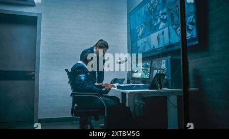 Female security worker have discussion with colleague in monitoring center, then leaves the office. African American CCTV operator works on computer with screens showing surveillance cameras footage. Stock Photo