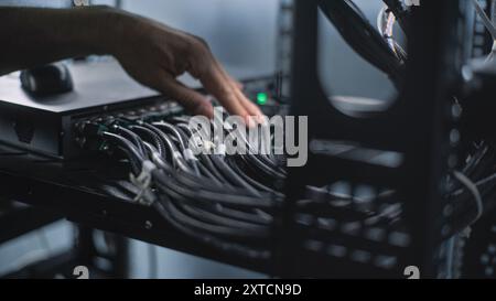Close up of system administrator connecting cables with server rack, working in server room. Maintenance of LAN or web servers. Operation of information systems and networks. Data storage center. Stock Photo
