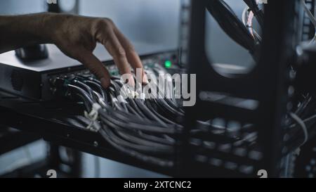 Close up of system administrator connecting cables with server rack, working in server room. Maintenance of LAN or web servers. Operation of information systems and networks. Data storage center. Stock Photo