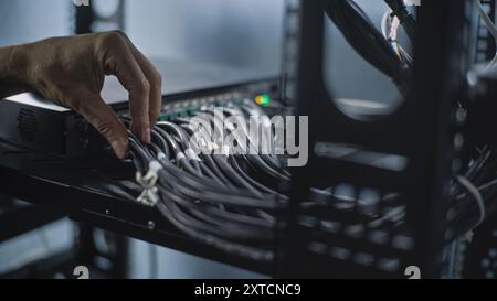 Close up of system administrator connecting cables with server rack, working in server room. Maintenance of LAN or web servers. Operation of information systems and networks. Data storage center. Stock Photo