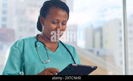 Confident Female Doctor Using Digital Tablet for Patient Information in Modern Medical Office Stock Photo
