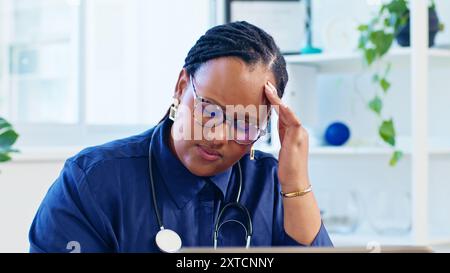 Stressed Doctor in Office with Glasses and Stethoscope Feeling Headache from Overwork and Fatigue Stock Photo