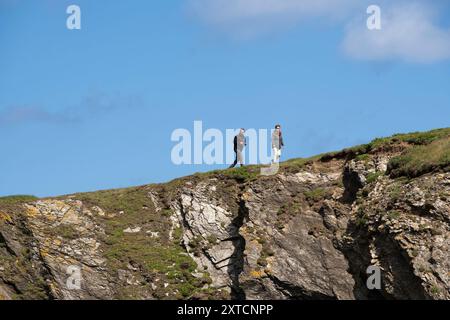 People holidaymakers tourists walkers walking on the cliffs on the coast of Pentire Point West in Newquay in Cornwall in the UK. Stock Photo